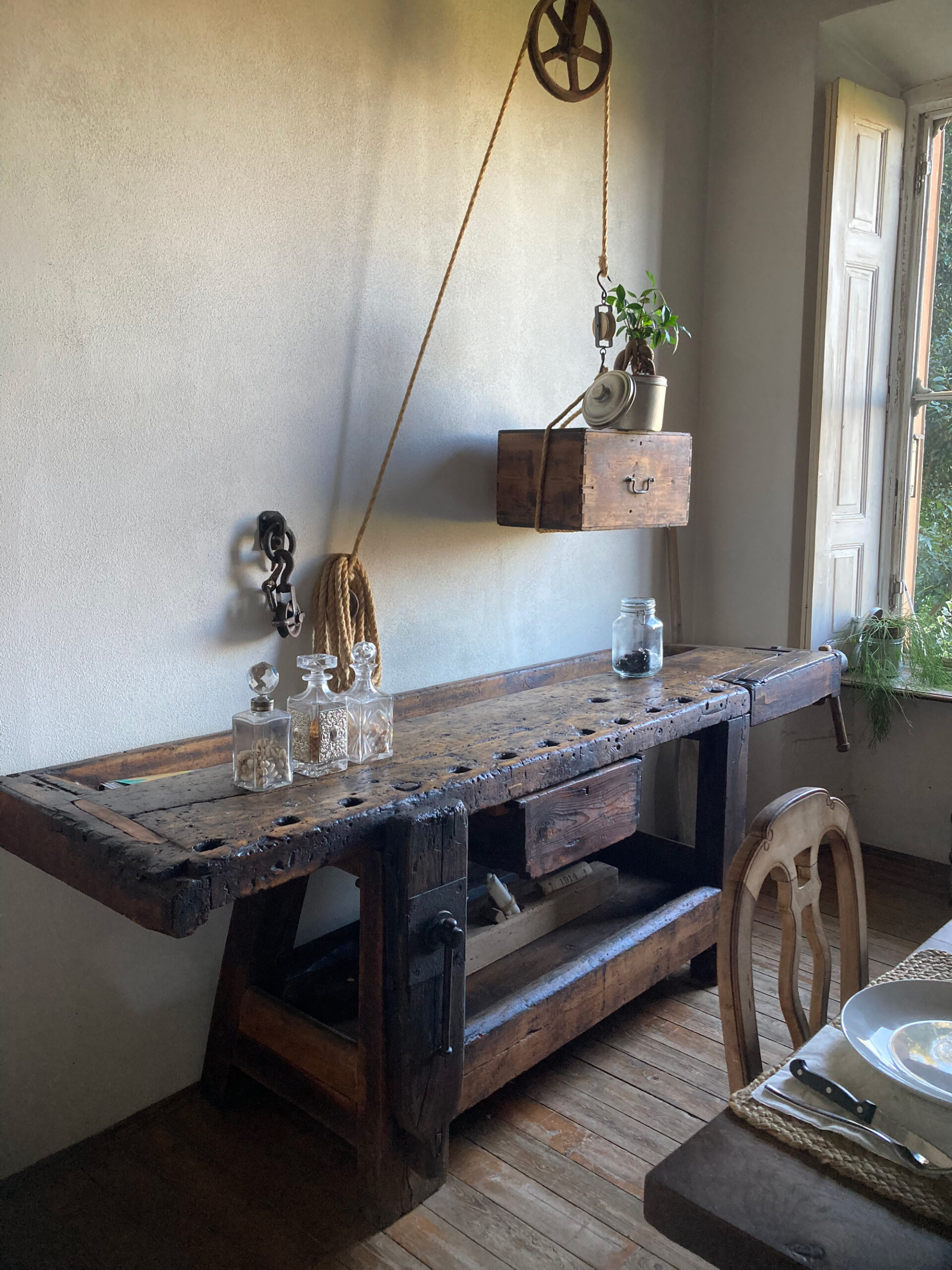 Consolle in legno rustico con oggetti decorativi accanto alla finestra