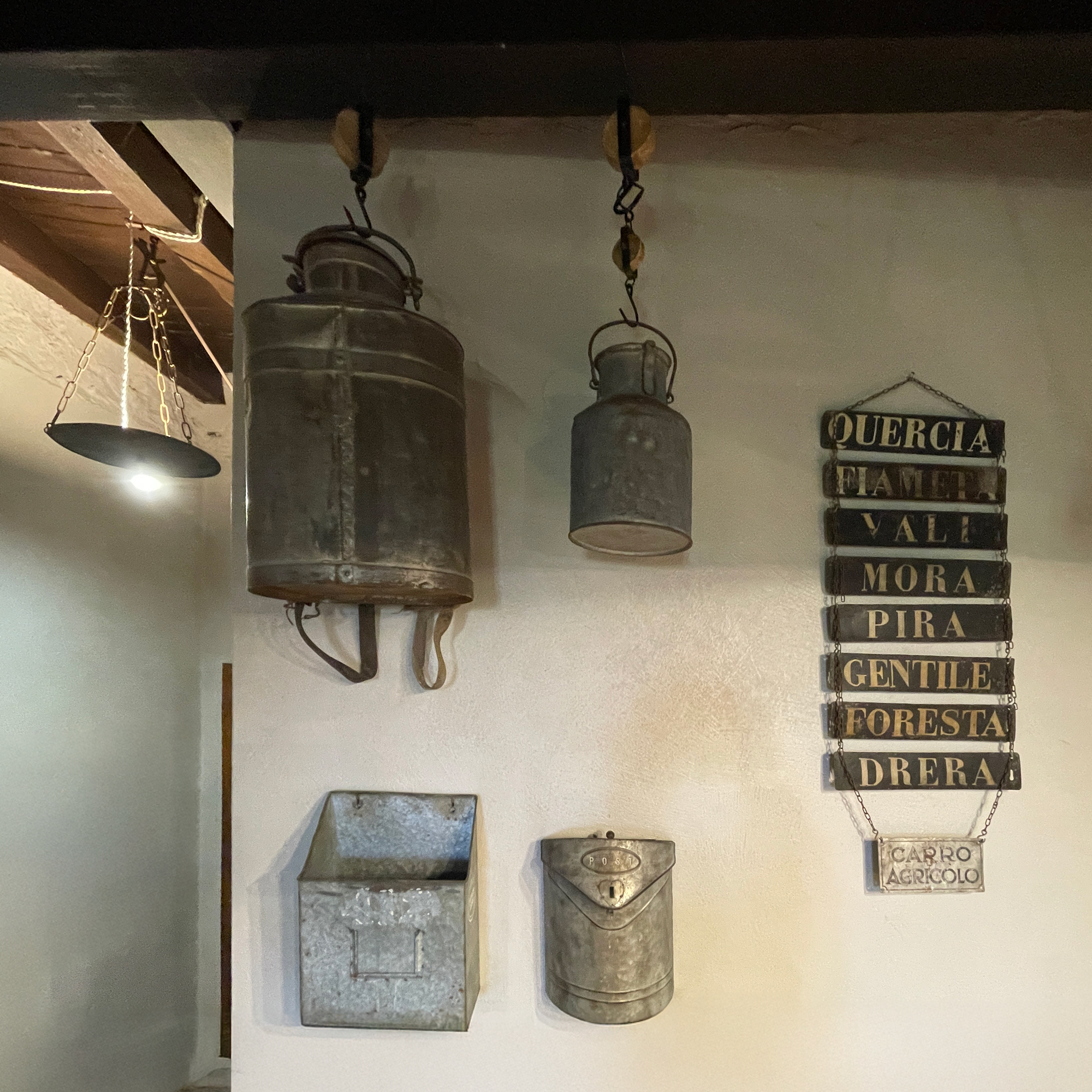 Lanterne, contenitori metallici e targhe decorative su una parete chiara