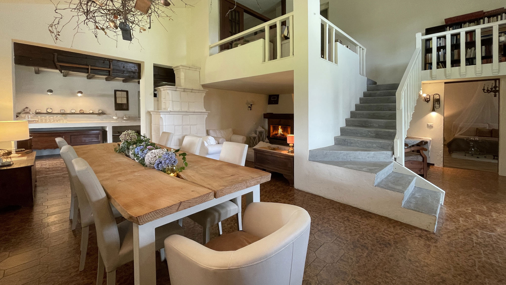 Sala da pranzo luminosa con tavolo in legno e scala bianca
