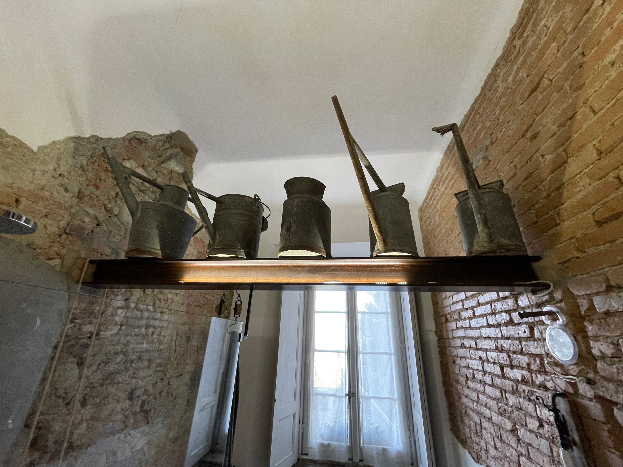 Scaffale con oggetti decorativi tra pareti in pietra e mattoni