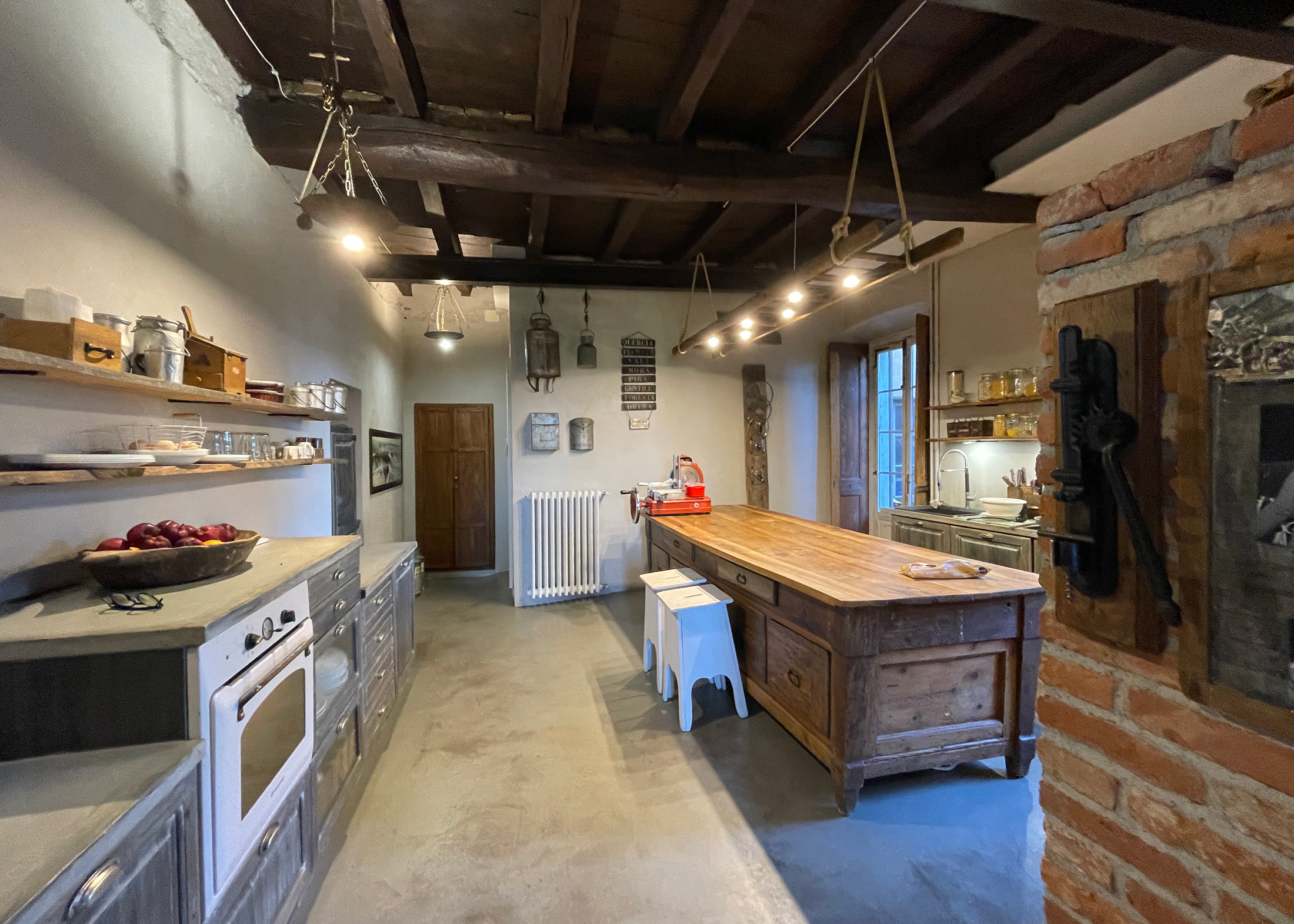 Cucina con grande tavolo in legno, muratura a vista e lampade sospese