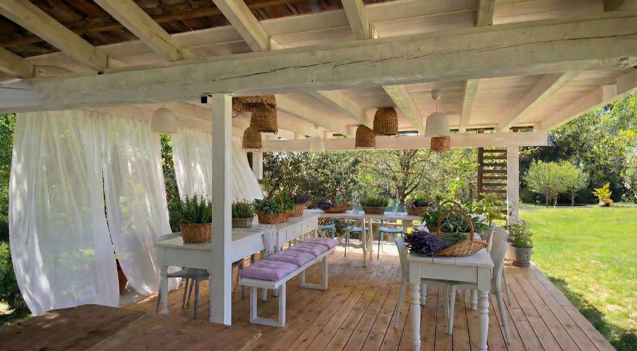 Portico arredato con tavoli, sedie e tende leggere affacciato sul giardino