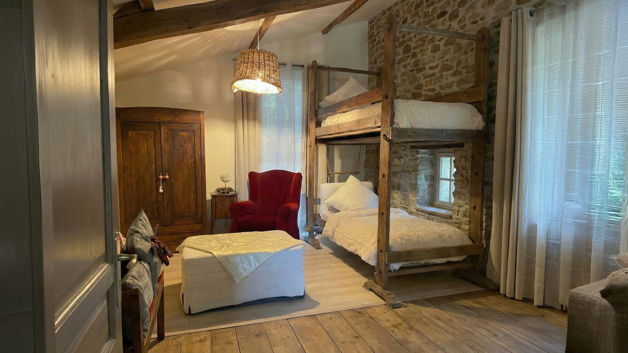 Camera con letto a baldacchino, parete in pietra e poltrona rossa