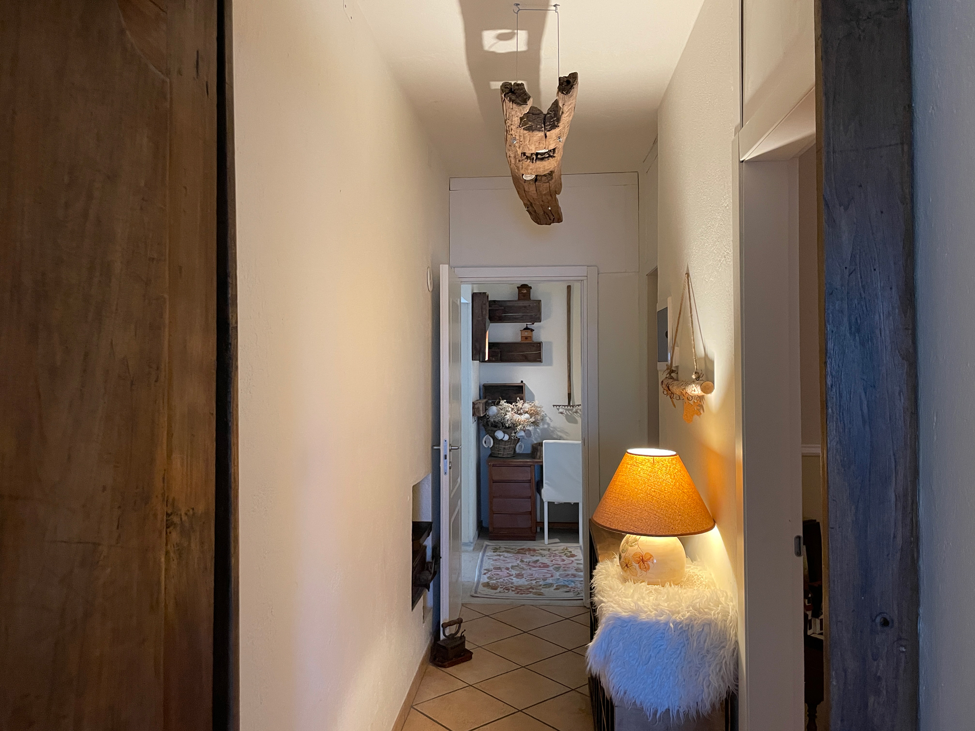 Corridoio con dettagli decorativi in legno e una lampada da tavolo accesa
